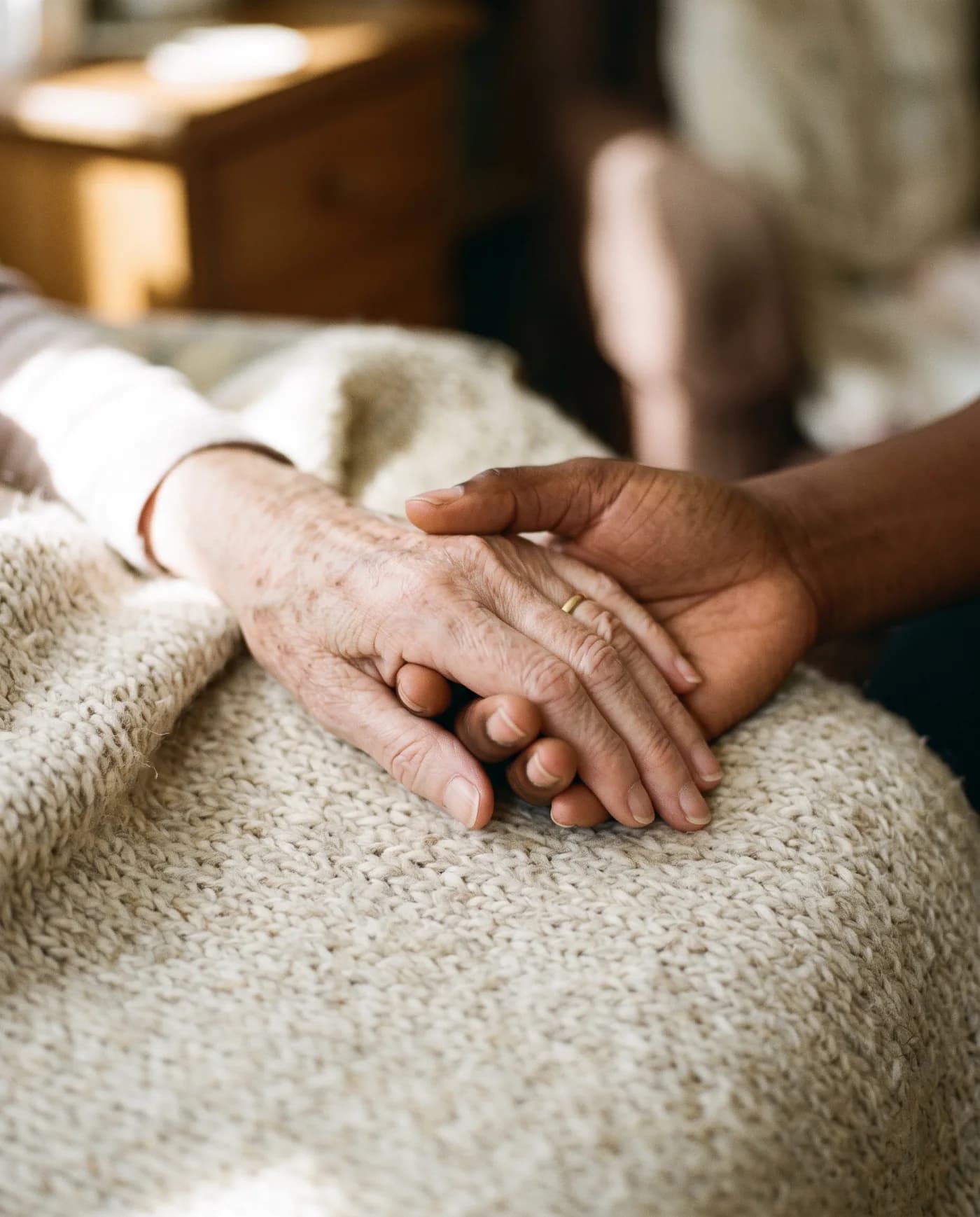 Zorgverlener houdt de hand vast van een oudere vrouw in bed